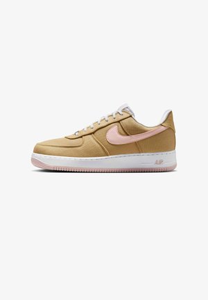 Laag profiel sneaker van beige stof met lichtroze Nike swoosh, witte veters, gewatteerde witte tussenzool en roze loopzoolprofiel.
