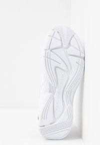 Semelle de chaussure de sport blanche en caoutchouc texturé, présentant un design ondulé et un logo sur la surface inférieure.