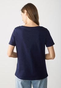 Mörkblå t-shirt med kort ärm och rund halsringning, i avslappnad passform, tillverkad av mjukt tyg, med en enkel och ren design.