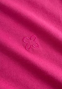 Fuchsia stof met een zachte textuur, voorzien van een klein geborduurd bloemmotief in een iets lichtere roze tint.