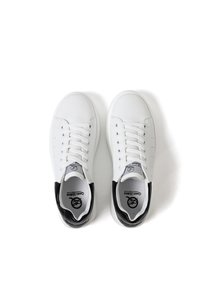 Sneakers bianchi con tomaia in pelle liscia, lacci piatti, perforazioni per traspirabilità e un accento sul tallone nero contrastante.