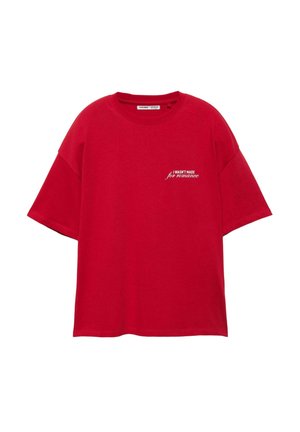 Červené oversized tričko s bílým nápisem "NEBYL JSEM STVOŘEN pro romantiku" na horní levé straně hrudi, kulatý výstřih a krátké rukávy.