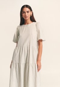 Robe légère rayée avec manches courtes bouffantes, encolure ronde, jupe à volants et coupe décontractée, confectionnée dans un tissu doux et texturé.