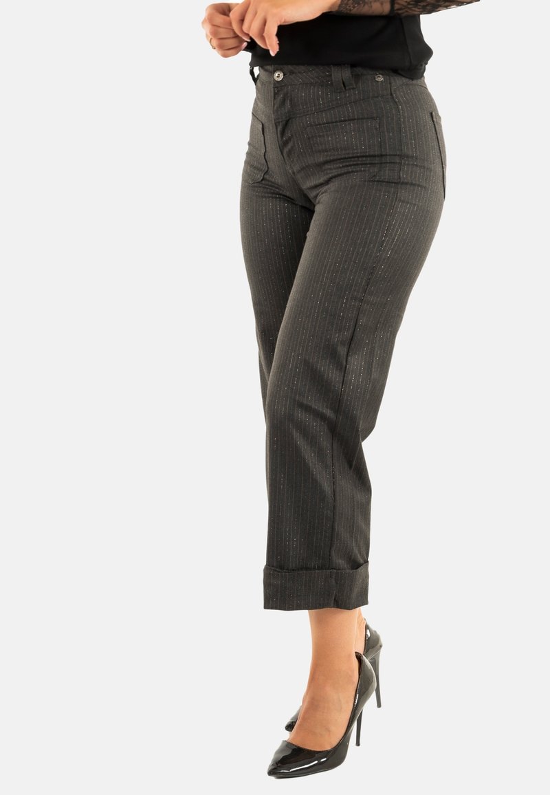 Pantalones de rayas grises con un ajuste entallado, que cuentan con bolsillos frontales y un dobladillo con puños. Llevados con unos zapatos de tacón negros.