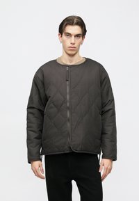 Mustast pehmest materjalist ümmarguse kaelusega, ees tõmblukuga tikitud jakk, millel on lõdvestunud lõige ja pikad varrukad.