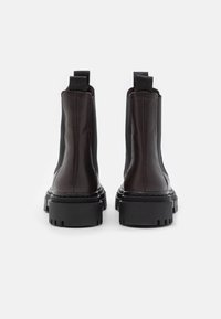 Black leather ankle boots with elastic side panels and thick rubber soles. Features contrasting stitching and tab accents for easy wear.