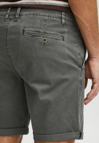 Shorts en coton gris avec des revers roulés, dotés d'une poche arrière avec un détail de bouton et de subtils accents cousus.