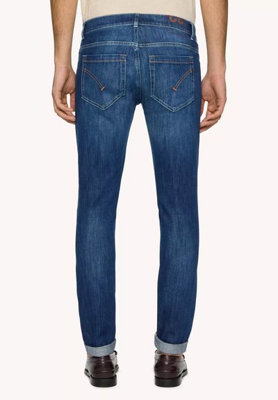 Jeans in denim blu con vestibilità affusolata, caratterizzati da tasche posteriori cucite, orlo arrotolato alle caviglie e dettagli di cucitura arancione.