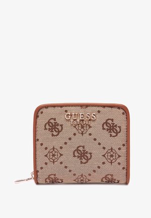 Portefeuille en tissu beige avec impression de logo marron, fermeture éclair et bord en simili cuir. Présente une marque dorée "GUESS EST 1981" sur le devant.