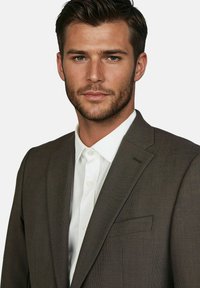 Donkerbruine op maat gemaakte blazer met een gestructureerde afwerking, enkele borstzak en geknipt revers, gedragen over een witte overhemd met kraag.