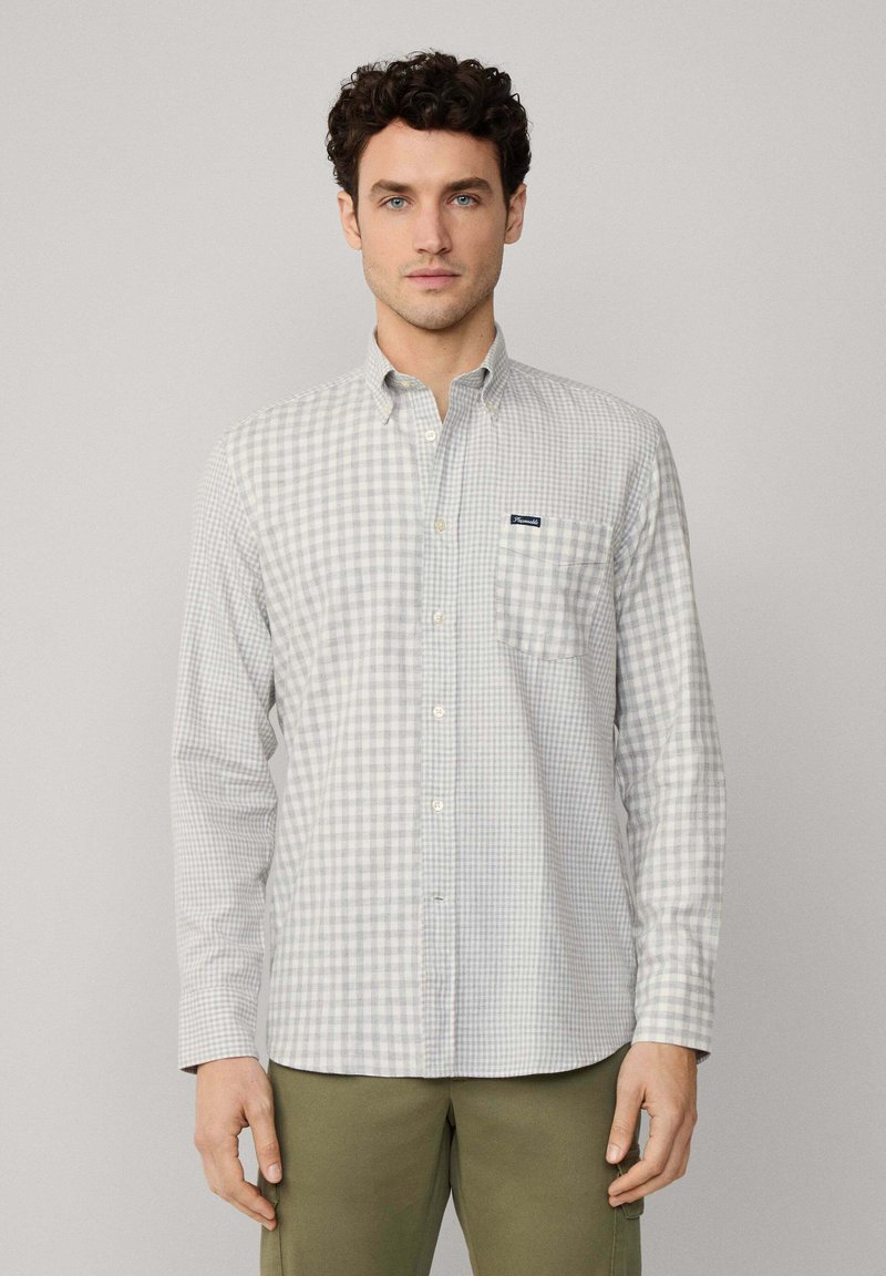 Camisa de botones en un patrón de cuadros en gris claro y blanco, con mangas largas, cuello y un bolsillo en el pecho que presenta una etiqueta de logo.