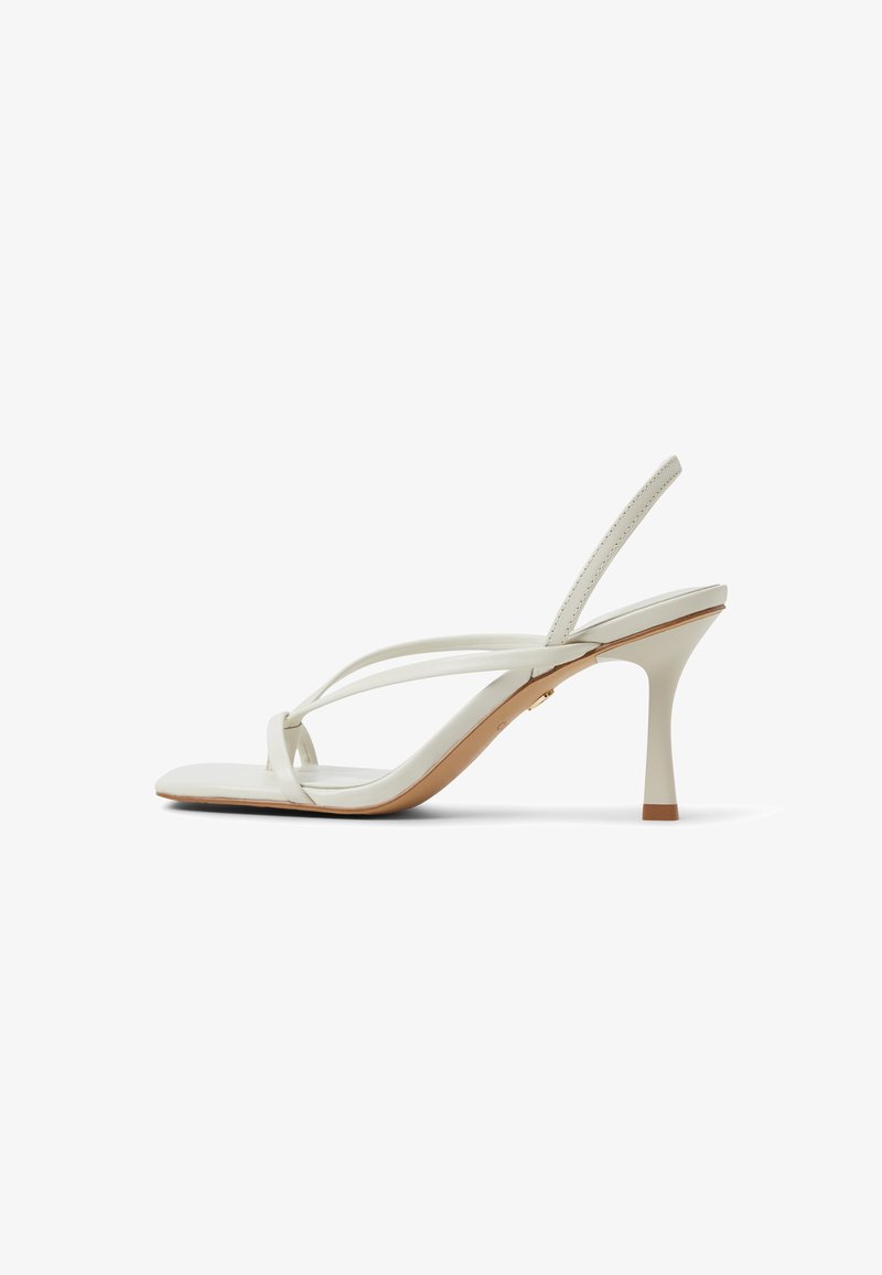 White leather heeled sandals with a sleek design, featuring thin crossed straps, a tapered heel, and a textured sole.