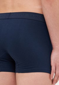 Mørkeblå boxershorts laget av myk bomull, med en teksturert linning med preget merkenavn og en tett passform.