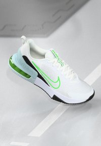 White athletic shoe with a mesh upper, green accents, and a distinctive black and mint sole. Features a visible air unit at the heel.