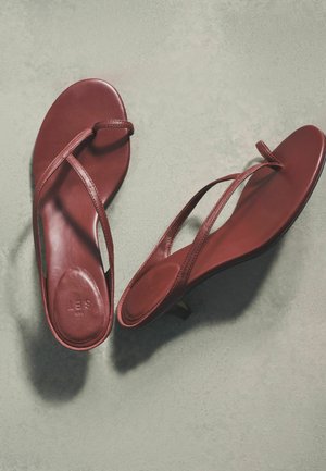 Pair of burgundy leather open-toe slingback sandals with thin straps, flat soles, and small heel on light gray surface.