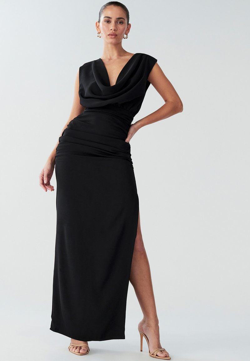Zwarte avondjurk met een gedrapeerde halslijn, korte mouwtjes en een hoge split aan de dij. Glad, rekbaar materiaal zorgt voor een getailleerd silhouet.