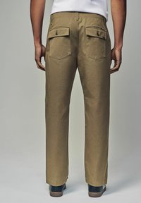 Pantaloni khaki con vestibilità dritta, realizzati in tessuto resistente, dotati di due tasche posteriori con bottoni e una texture liscia.
