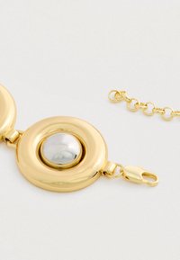 Pulsera de cadena de oro con un eslabón central redondo, brillante y suave que presenta una cúpula plateada reflectante y un cierre de langosta.