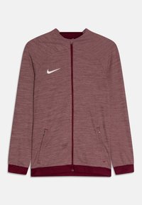 Bordeaux Nike-jack met een gestructureerde afwerking, ritssluiting aan de voorkant, hoge kraag, twee zijzakken en een wit logo op de borst. Kleurcontrast bij de manchetten.