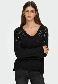 Pull noir avec un col en V, orné de paillettes noires sur les épaules, doté de manches longues et d'un ourlet côtelé.
