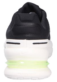 Basket noir avec une tige en maille texturée, une semelle blanche épaisse et une unité d'amortissement vert fluo visible au niveau du talon.