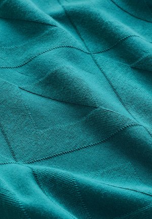 Teal värviline tekstureeritud kangas lainelise mustriga, näidates pehmeid kudumismaterjale ja nähtavaid õmbluse detaile, rõhutades selle katsumist.