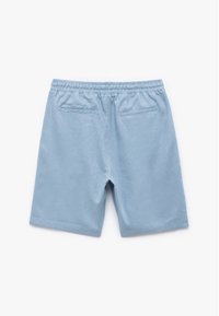 Pantalones cortos de color azul claro, hechos de una tela suave, con una cinturilla elástica y dos bolsillos traseros con una textura simple y suave.