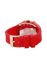 Reloj de pulsera de silicona roja con una correa texturizada, hardware en tono dorado y un fondo transparente que muestra el logo de la marca y detalles de resistencia al agua.