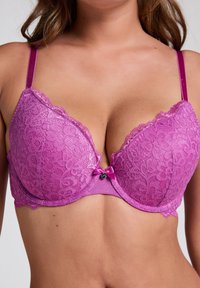 Behå med spetser av ljuslila färg, med blommönster, justerbara satinband och en liten satinrosett i mitten.