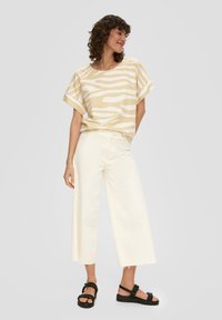 Beige und weiße gestreifte Kurzarmbluse, kombiniert mit creamfarbenen weitem Hosen und schwarzen Plateausandalen mit geflochtenen Akzenten.