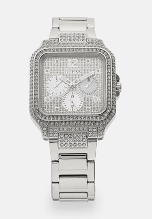 Orologio rettangolare argentato con accenti di cristallo, tre quadranti secondari e bracciale a maglie metalliche. Cassa trasparente con un motivo a griglia e indicatori argentati.