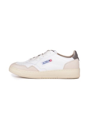 Baskets en cuir blanc avec des accents en daim beige, une semelle en caoutchouc plate et une zone de orteil perforée. Présente un logo bleu et rouge sur le côté.
