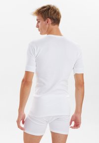 Hvid bomulds t-shirt med korte ærmer, der har en rund halsudskæring og ribbede manchetter. Glat tekstur og tætsiddende design.