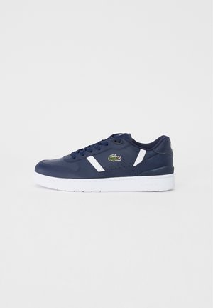Marineblå sneaker med hvid sål, hvide sidestriber og grønt krokodillelogo på siden, vist i profil.