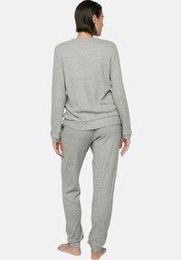 Ensemble de loungewear en gris à côtes composé d'un haut à manches longues et d'un pantalon fuselé. Tissu doux et léger avec une coupe décontractée et une taille élastique.