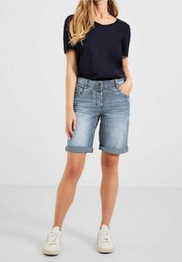 Ljusblå denimshorts med randigt mönster, uppvikta kanter, två framfickor och knappstängning. Matchas med en marinblå kortärmad topp.