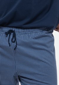 Marineblauwe en lichtblauwe geruite shorts met een elastische tailleband en koord. Lichte stof met een ontspannen pasvorm.