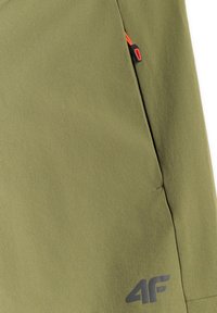 Tissu vert olive avec un petit tirette de fermeture éclair rouge sur une poche et un logo "4F" gris foncé près du bord inférieur.