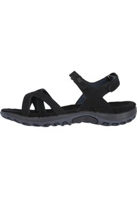Musta sandaali, jossa on nyöritysdesign, säädettävä velcro-hihna, pehmustettu pohja ja teksturoitu kumipohja pitävää otetta varten.