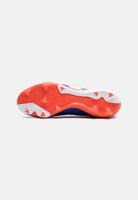 Suela de botas de fútbol Predator: goma texturizada en rojo-naranja con acentos en blanco, tacos triangulares y detalle en relieve "PREDATOR".