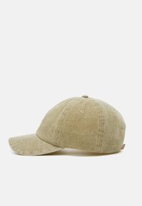 Kaki baseball cap laget av teksturert stoff, med en buet brem, seks sømmer og en logo brodert på fronten.
