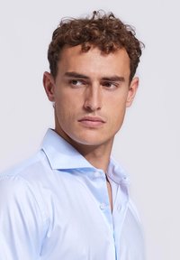  Lichtblauw overhemd met een gestructureerde kraag, gladde stof en verschillende knopen aan de voorkant. Korte mouwen en aansluitende pasvorm.