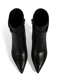 Bottes bottines en cuir noir avec un bout pointu, une texture lisse, une fermeture éclair latérale et un design minimaliste.