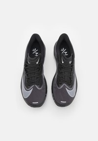 Baskets de sport noires et grises avec une tige en mesh, des détails texturés et un logo Swoosh argenté bien en vue. Lacets noirs et semelles rembourrées.