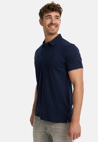 Marineblaues Poloshirt aus Baumwolle mit Kragen, kurzen Ärmeln und einem dezenten gestickten Logo auf der Brust.