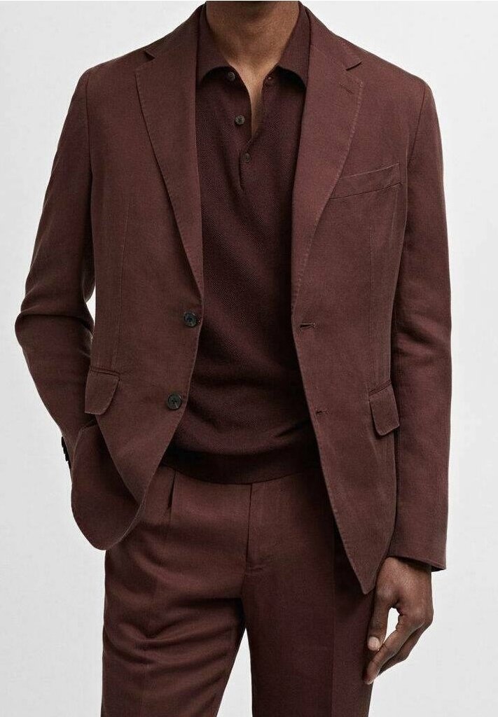 Homme portant un costume marron foncé avec un pantalon assorti et un polo marron foncé boutonné, debout avec une main dans la poche.