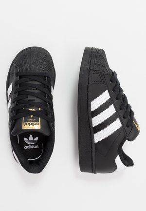 Sorte Adidas sneakers med hvide striber og sorte snørebånd, vist fra top- og sidevisning på hvid baggrund.