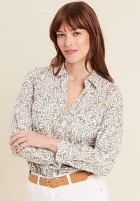 Lange mouwen shirt in lichtgrijs met een wit bladerenpatroon, voorzien van een button-down kraag, twee borstzakken en gecombineerd met een beige riem.