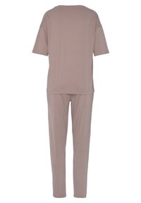 Two-piece loungewear set in light taupe, featuring a loose-fitting short-sleeve top and matching tapered pants made of soft fabric.