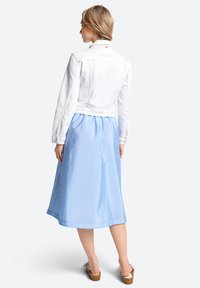 Weiße Denimjacke mit tailliertem Schnitt, kombiniert mit einem hellblauen, knielangen Rock aus einem glatten, glänzenden Stoff.